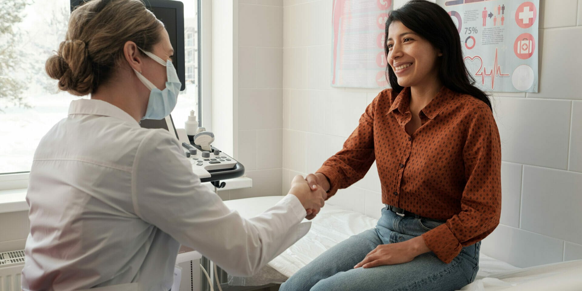 Female clinician shaking hand of young happy Hispanic patient Female clinician shaking hand of young happy Hispanic patient sitting on couch in medical office after ultrasound examination